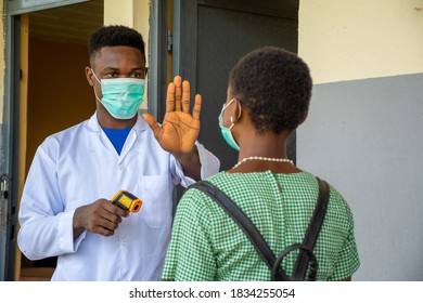 African School Teacher Stops A Pupil For Body Temperature Check Before Entering The Classroom