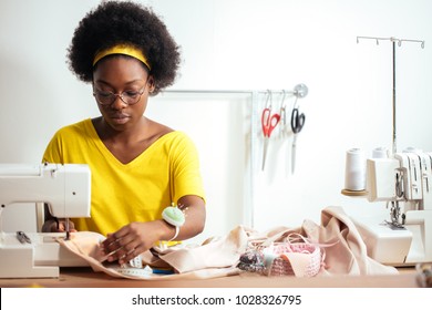 african seamstress sews clothes. Workplace of tailor - sewing machine, rolls of thread, fabric, scissors. - Powered by Shutterstock