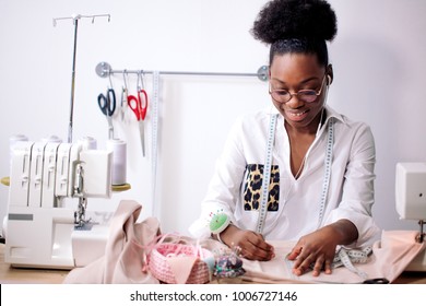 african seamstress working with pink fabric takes measures