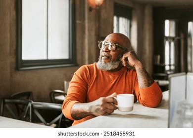 African senior man drinking coffee at bar. Coffee break with a hot coffee in a cup.  African American senior man having a coffee in a rustic cafe in London. Retired black senior man. - Powered by Shutterstock