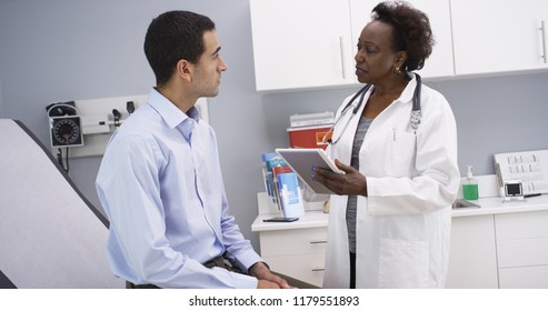 African senior medical doctor using elctronic notebook to take notes of patient