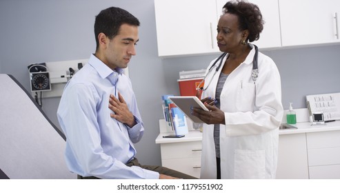 African senior medical doctor using elctronic notebook to take notes of patient