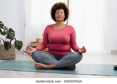 African senior woman doing pranayama breath exercises during yoga session at home - Focus on face