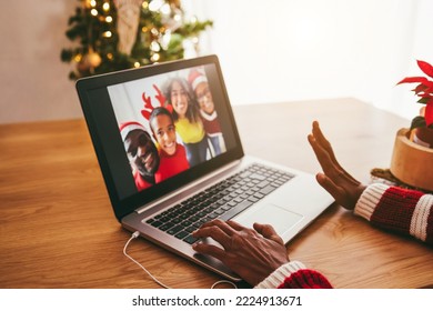 African senior woman doing video call with her family during Christmas time - Focus on left hand - Powered by Shutterstock