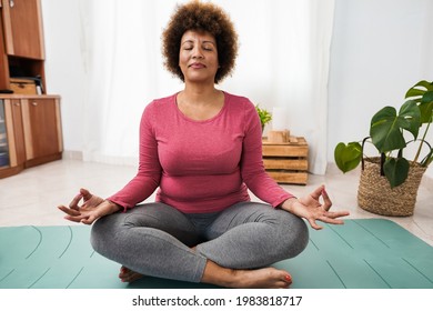 African senior woman doing yoga session at home - Focus on face - Powered by Shutterstock