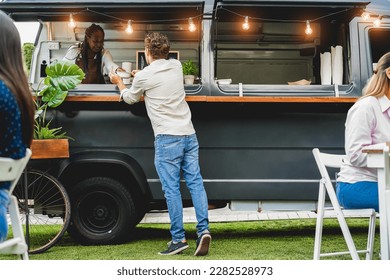 African senior woman serving take away food inside food truck - Focus on customer head - Powered by Shutterstock