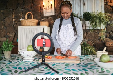 African Senior Woman Streaming Online Vegetarian Cooking Virtual Masterclass Lesson Outdoors At Home - Focus On Hands