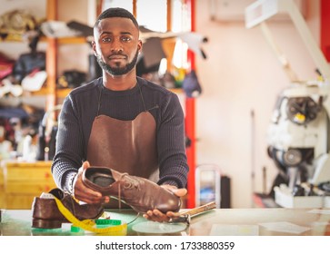 An african shoemaker works in his shop. Close-up of the shoemaker in the artisan/commercial business counter.