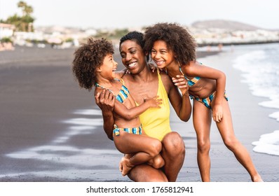 African sisters daughters on the beach with smiling mother - Black family people having fun on summer time - Vacation, travel and happiness lifestyle concept - Main focus on mum face