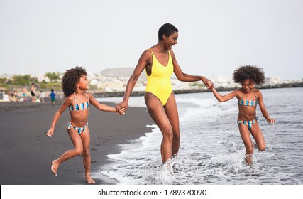 African Sisters Twins Running On The Beach With Smiling Mother - Black Family People Having Fun On Summer Time - Vacation, Travel And Happiness Lifestyle Concept - Main Focus On Mum Face