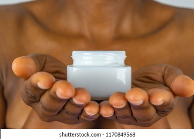 African Skin Care. African American Woman Taking Care Of Her Dry Brown Skin Complexion. Moisturizing Cream In Black Female Hands Isolated. Beauty Treatment.