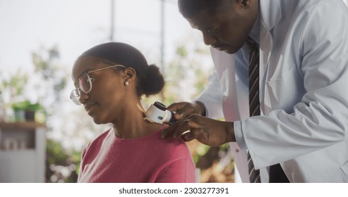 African Skin Care Professional Using a Dermatoscope to Examine Neck Tissue on the Skin of an Attractive Young Black Female During a Health Check Visit to a Clinic - Powered by Shutterstock