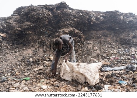 African slum boy collecting reusable items in a garbage dump; symbol of poverty in developing countries