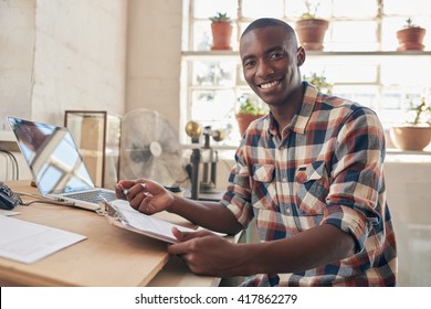 African Small Business Owner And Entrepreneur Smiling At His Desktop