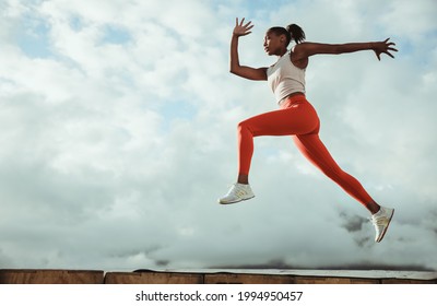 African sportswoman doing running and lunge exercise workout on rooftop. Female athlete doing workout on building terrace. - Powered by Shutterstock