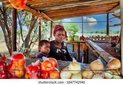 african street vendor, mother and child, selling onions, cabbage, tomatoes.