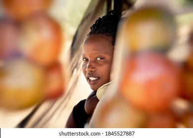 african street vendor, mother holding her child between the bags of tomatoes