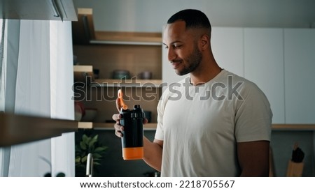 African strong healthy sports man male sport athlete bodybuilder trainer guy in kitchen smile drinking liquid calcium vitamins dietary supplements clean water protein aqua with plastic fitness bottle Stok fotoğraf © 