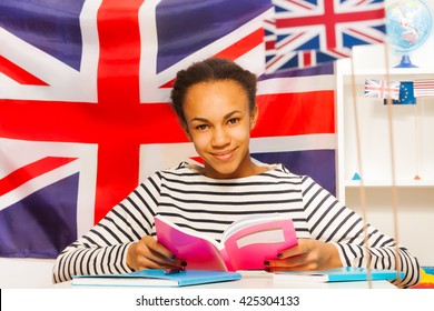 African student in frock reading book at the class