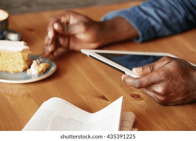 African Student Spending Morning At A Cozy Cafe, Having Breakfast, Reading E-book Or Texting With Friends Using Digital Tablet With Copy Space Screen For Your Information. Selective Focus On The Hand