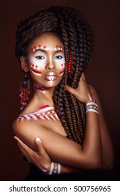 African style woman . Attractive young woman in ethnic jewelry with drum. close up portrait. Portrait of a woman with a painted face. Creative makeup and bright style.
