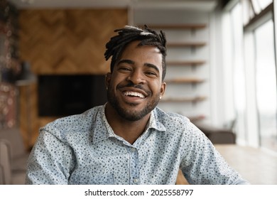 African stylish hipster guy with dreadlocks hairstyle wide toothy smile sit indoor look at camera. Video call event profile picture, portrait of successful entrepreneur pose in modern office concept - Powered by Shutterstock