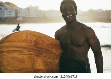 African Surfer Man Holding Vintage Surf Board On The Beach At Sunset - Focus On Face