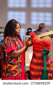 African tailor preparing a vibrantly patterned dress on a mannequin in a workshop