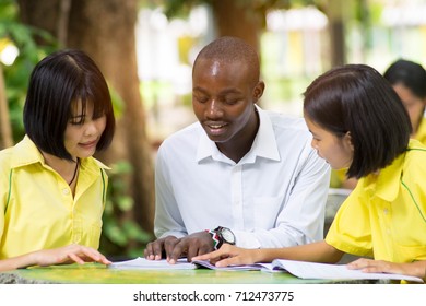 African Teacher Teaching Asian Student About Foreign Languages.