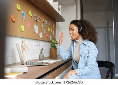 African Teen Girl Student Wear Headphones Waving Hand Video Conference Calling Online On Laptop Computer At Home Office. Elearning Zoom App Video Call, Distance Videoconference Class With Teacher.