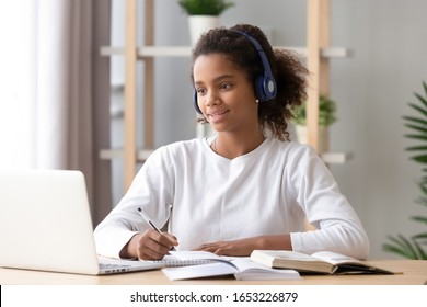 African teen girl wearing headphones study with internet chat skype teacher prepare for exam, black girl school student learning online, watch webinar make notes looking at laptop, distance education - Shutterstock ID 1653226879