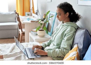 African Teen School Girl Student Virtual Distance Learning Online Digital Class Looking At Laptop Sitting On Bed At Home. Mixed Race Gen Z Teenager Remote Using Computer, Typing, Elearning In Bedroom.