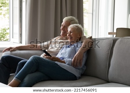 African teenage couple relaxing on couch spend carefree weekend together at home, hold remote control switch channels enjoy movie or favourite TV show using online streaming services. Leisure concept