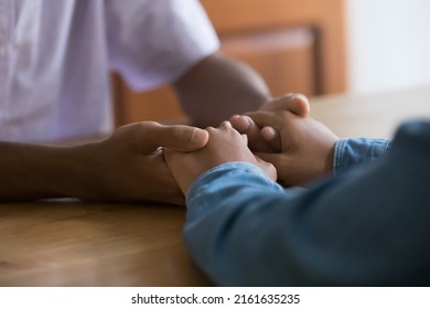 African Teenage Dating Couple Having Serious Talk, Sitting At Table, Holding Hands. Loving Parent Giving Sympathy, Help, Psychological Support To Kid. Arms Close Up, Cropped Shot