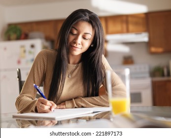 african teenager girl doing homework in kitchen before school