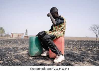 African teenager strained for walking long distance to collect clean water. Water scarcity and drought symbol. - Shutterstock ID 2138413543