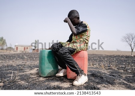African teenager strained for walking long distance to collect clean water. Water scarcity and drought symbol.