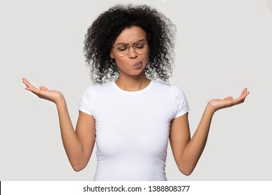 African thoughtful woman in glasses white t-shirt stretched hands imagining alternatives weighs pros and cons isolated on grey blank background, concept of make important decision and choosing option - Shutterstock ID 1388808377