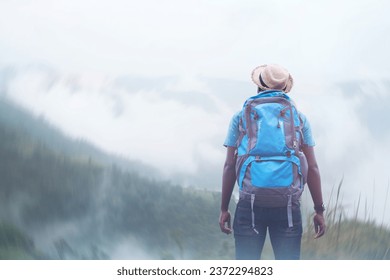 African traveler man in hat standing and looking to the beautiful nature of the mountains on a foggy day.Adventure travel and success concept - Powered by Shutterstock