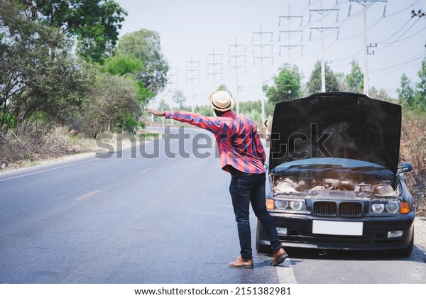 African traveler man raising hands for help\
because his car is broken side the\
highway