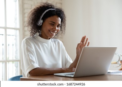 African tutor of language start on-line lesson with trainee wave hand smiling looks at pc screen. Mixed-race woman in headphones communicating distantly, e-learning process, application usage concept - Shutterstock ID 1687244926