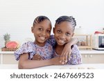 African twin girl sister with curly hair braid African hairstyle hugging each other at home kitchen. Happy smiling kid sibling showing love with hugs. Cute children in family spend time together.