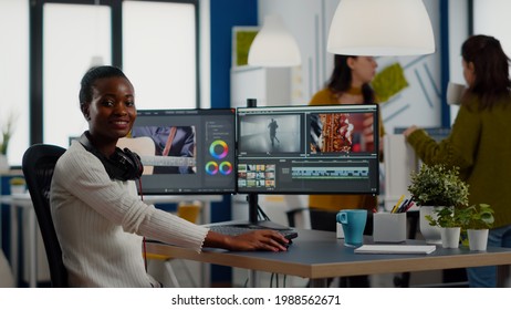 African video editor looking at camera smiling editing video project in post production software working in creative studio office. Videographer editing audio film montage on professional computer - Shutterstock ID 1988562671