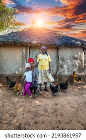 African Village Family Three Generations In Front Of The House With The Thatched Roof, Chickens Running Around