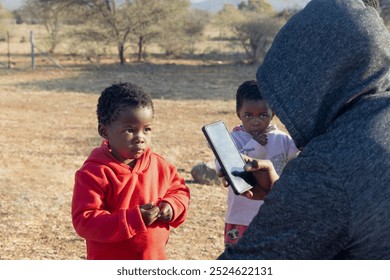 african village , social worker volunteer for NGO taking pictures of african children in the field outdoors - Powered by Shutterstock