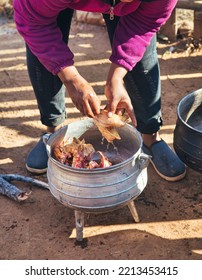 African Village Woman Preparing Chicken On The Side Of The Road In Cast Iron Pots