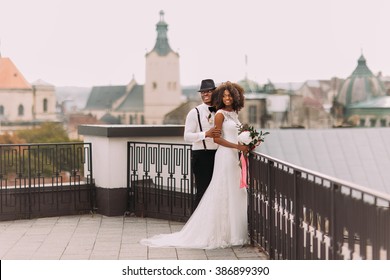 African Wedding Couple On The Rooftop. Amazing European Lviv Architecture On Background