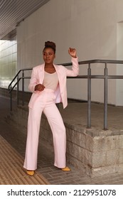 African Woman With Afro Hair Wearing Pink Summer Suit  Posing Outside At Urban Minimalist Background. Glamorous And Modern Style Runaway Full Length Portrait. Modeling And 2022 Fashion Concept.