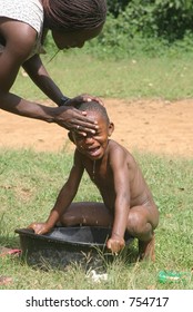 African Woman Bathing Her Child Outdoors