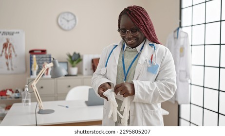 African woman with braided hair doctor putting gloves for safety at clinic - Powered by Shutterstock